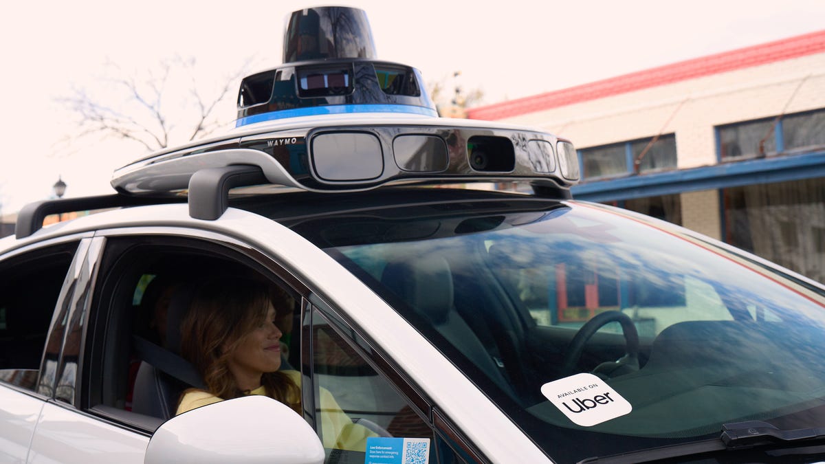A Waymo-operated Jaguar I-Pace with an Uber sticker in the window
