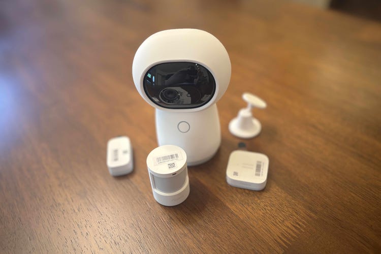 Aqara's camera security system pieces on a wood table.