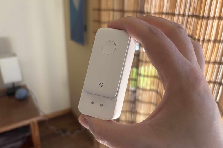 A hand holds the SwitchBot leak detector up.