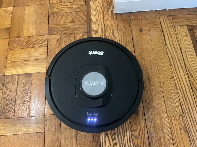 Shark's robot vacuum on a wooden floor.