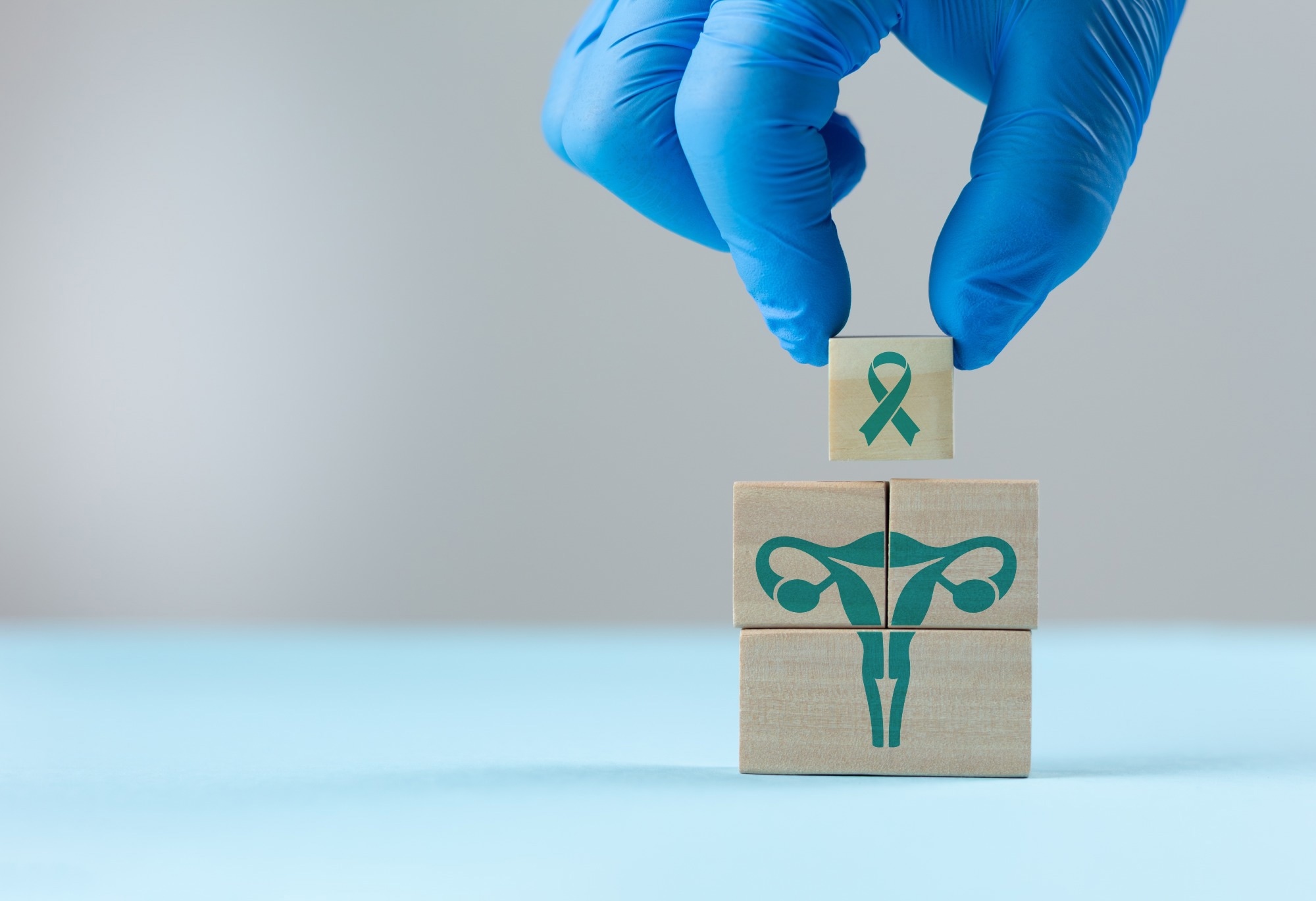 Uterine health. A doctor wearing a blue glove places wooden cubes with a uterus icon. Concept of cervical cancer prevention and early detection, gynecological care, and women