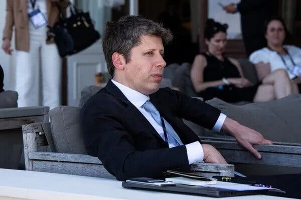 Sam Altman, wearing a dark suit, sits in a large chair.