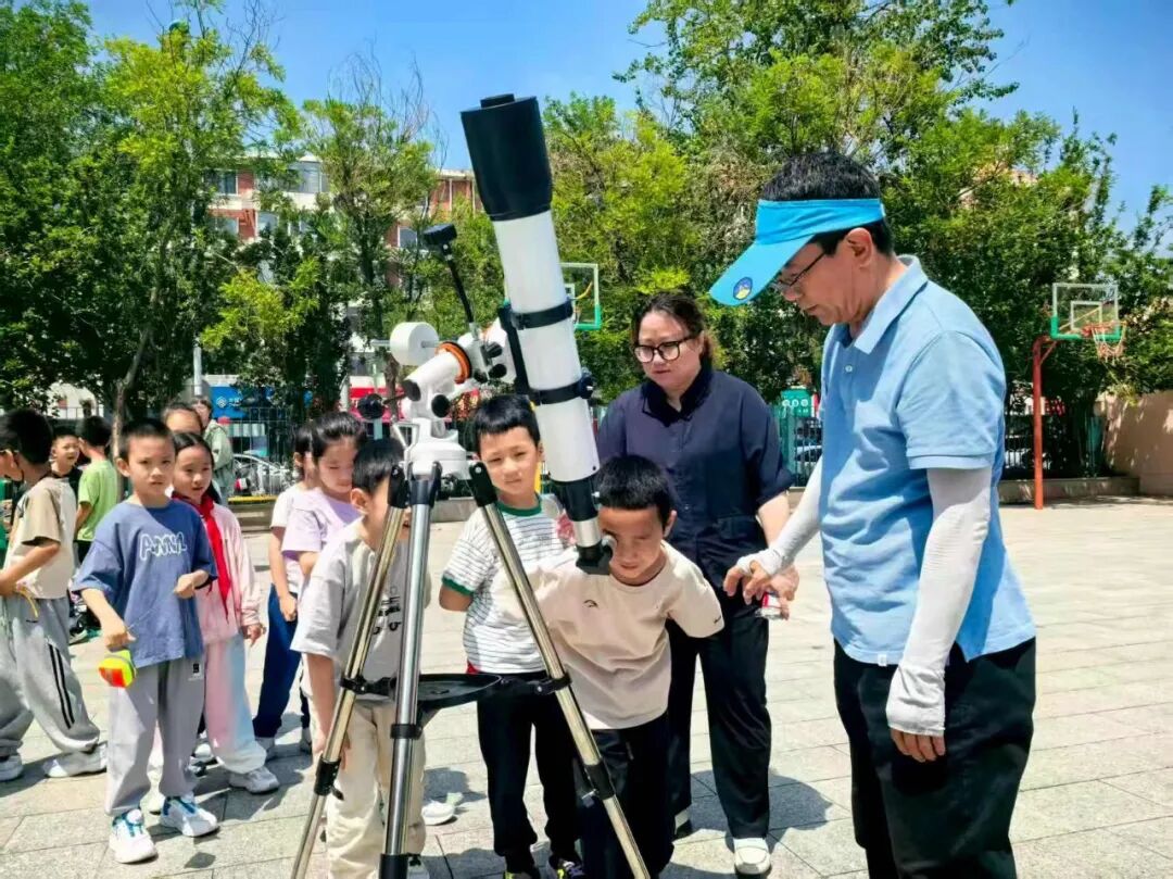 天津市天文学会理事长阎为国（右一）在天津市平山道小学指导孩子们观测太阳黑子。受访单位供图