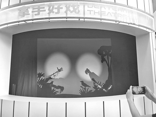 　　机器人在消费街区表演手影戏。
