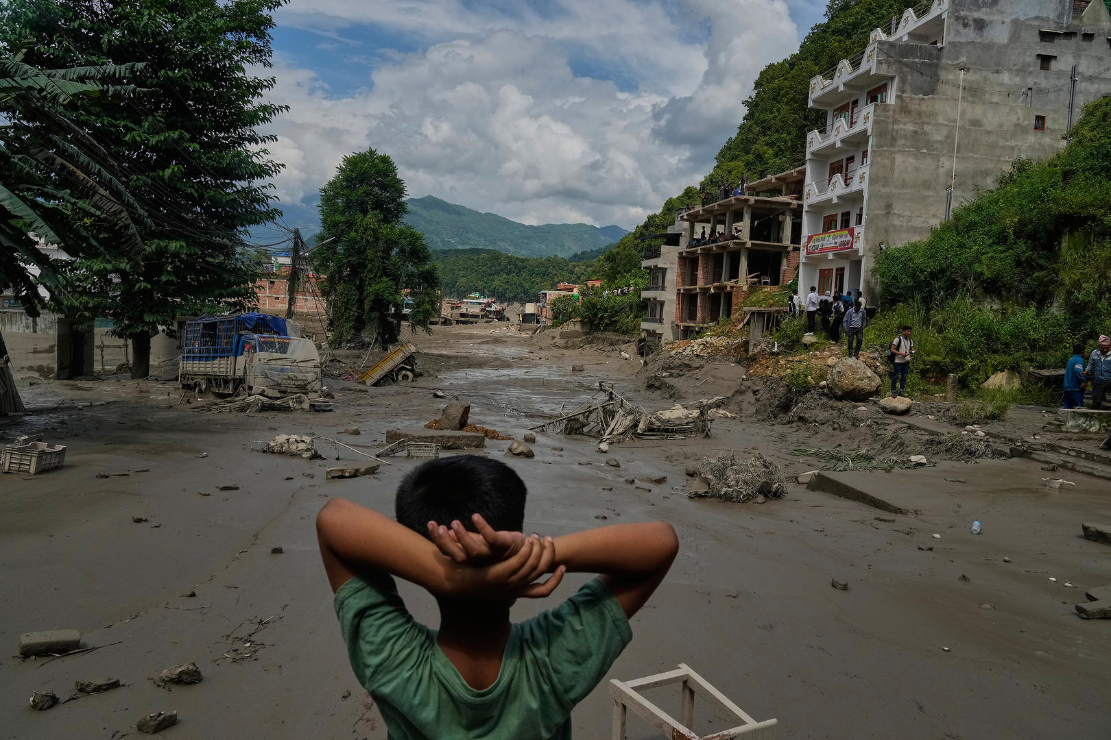 ▲当地时间2026年8月26日，尼泊尔努瓦果德地区，一名男孩看着特里苏里河洪水造成的破坏（图据视觉中国）