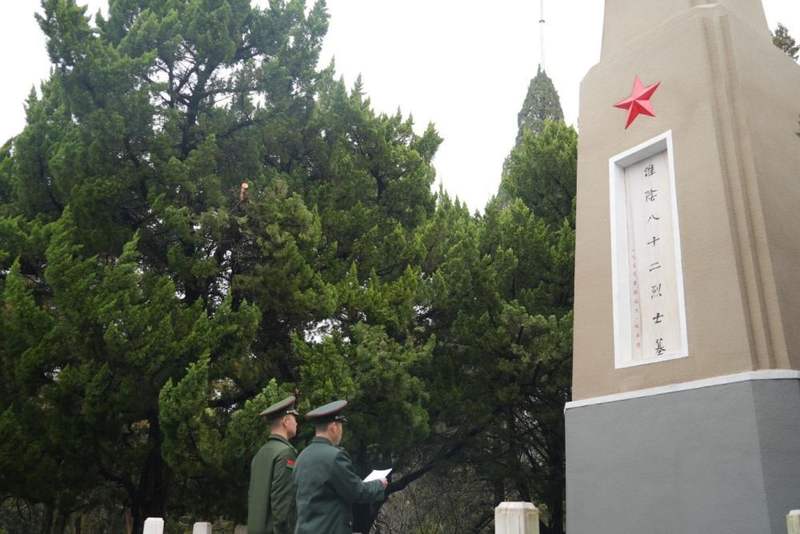 ↑2026年3月18日，朱敬轩（右）在牺牲的八十二位烈士的墓前读手写信。李彧绰 摄
