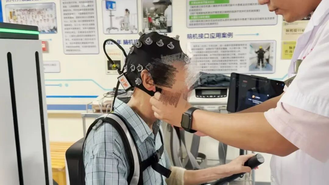 图为 安徽省第二人民医院人工智能创新场景中,一名脑卒中患者在康复师指导下使用爱博智能脑机接口康复产品
