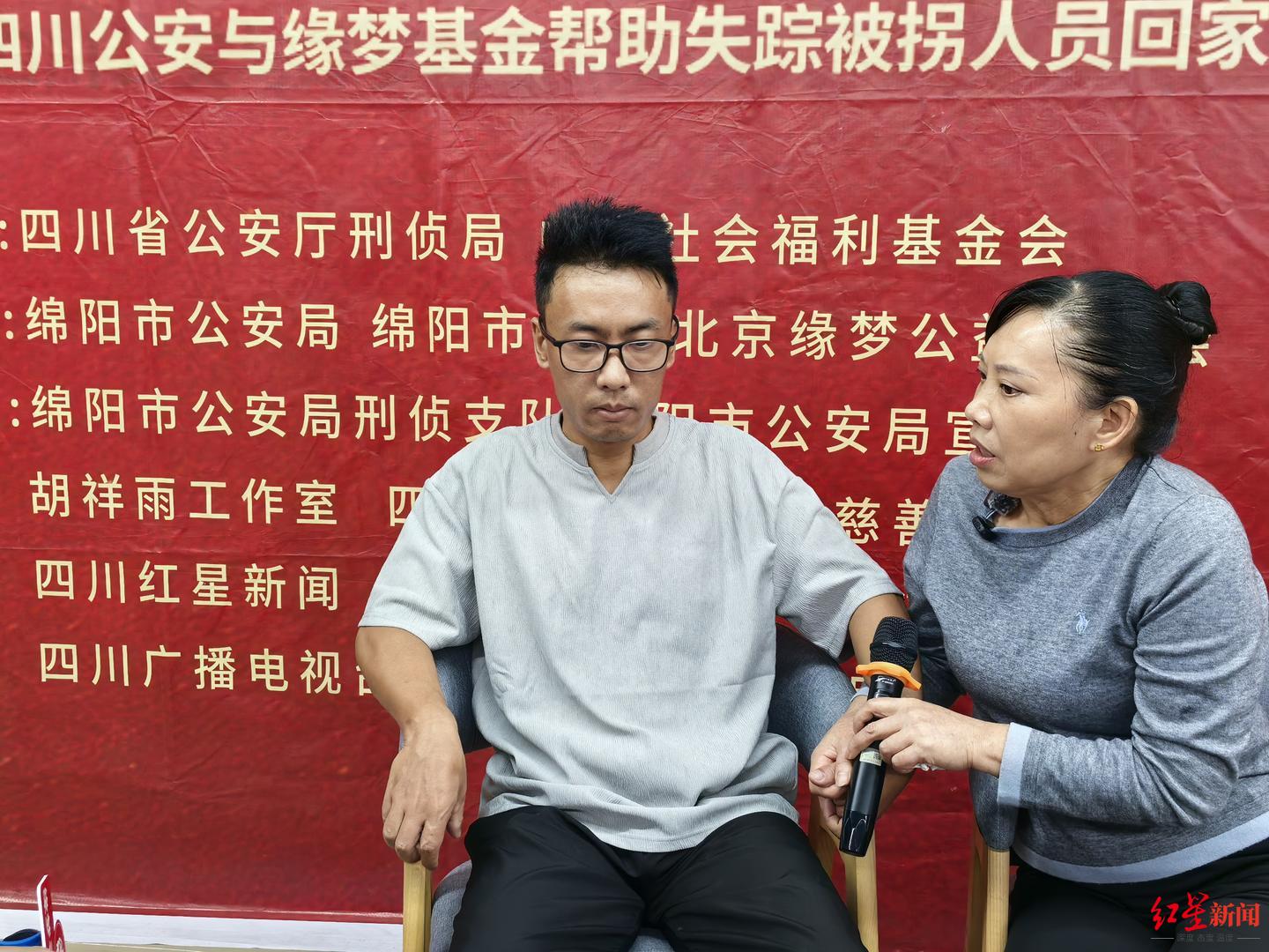 ▲认亲团圆现场，刘华清紧紧拉着儿子的手